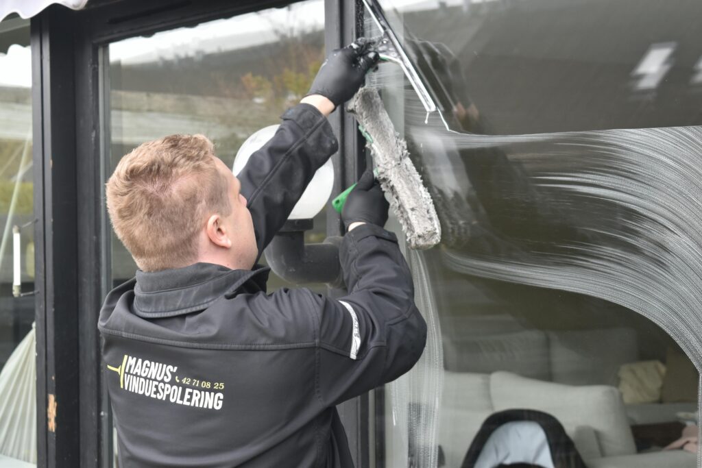 Professional cleaning service washing a large glass window. Clean and efficient work by a dedicated individual.